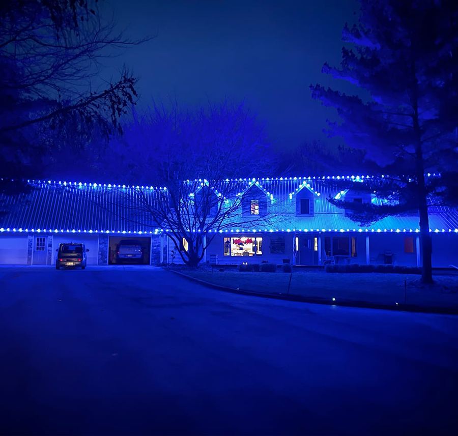 Home with wraparound porch lit with blue holiday lights